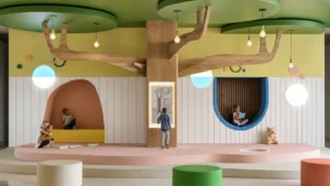 Kids Space Design Details: 7 Powerful Ideas That Make Children’s Interiors Feel Calmer 11 Kids space design details at The Tree Spot with a tree-inspired wall, blue reading nook, pendant lights, soft seating, and calm activity zones.